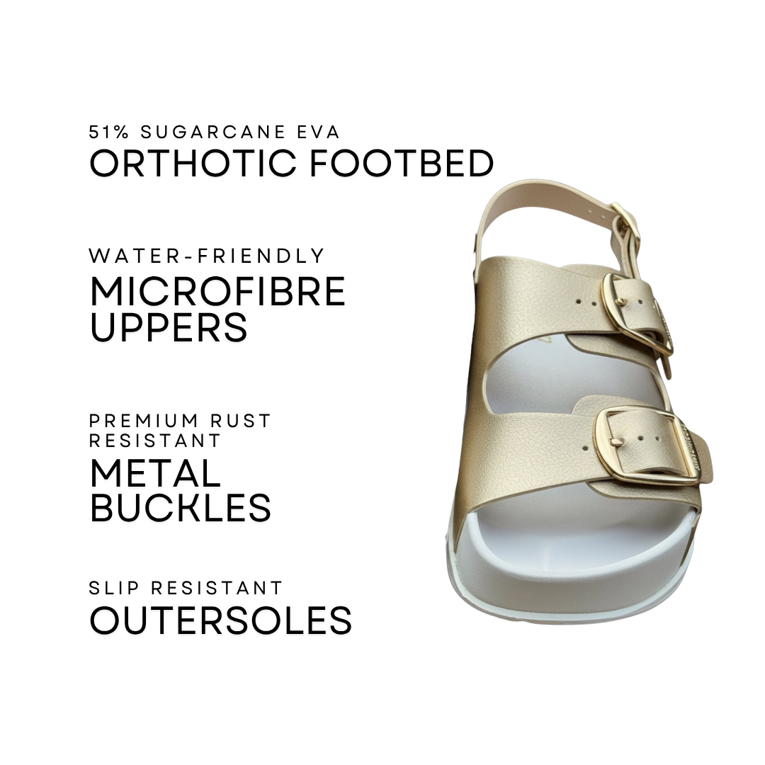 A single metallic champagne-gold double-strap sandal shown on a white background with black text callouts describing features such as an orthotic footbed, water-friendly microfiber uppers, rust-resistant metal buckles, and slip-resistant outsoles.